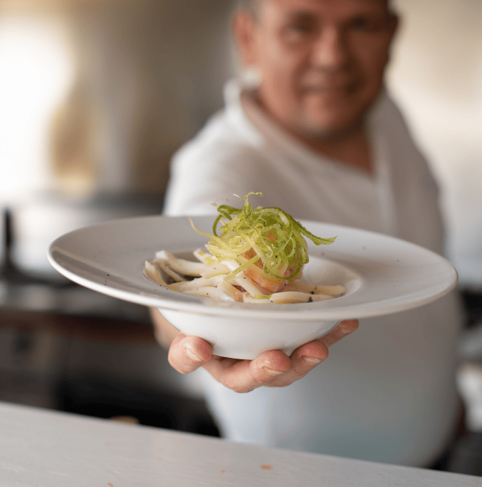 piatto di mare offerto in primo piano alla vista da un addetto