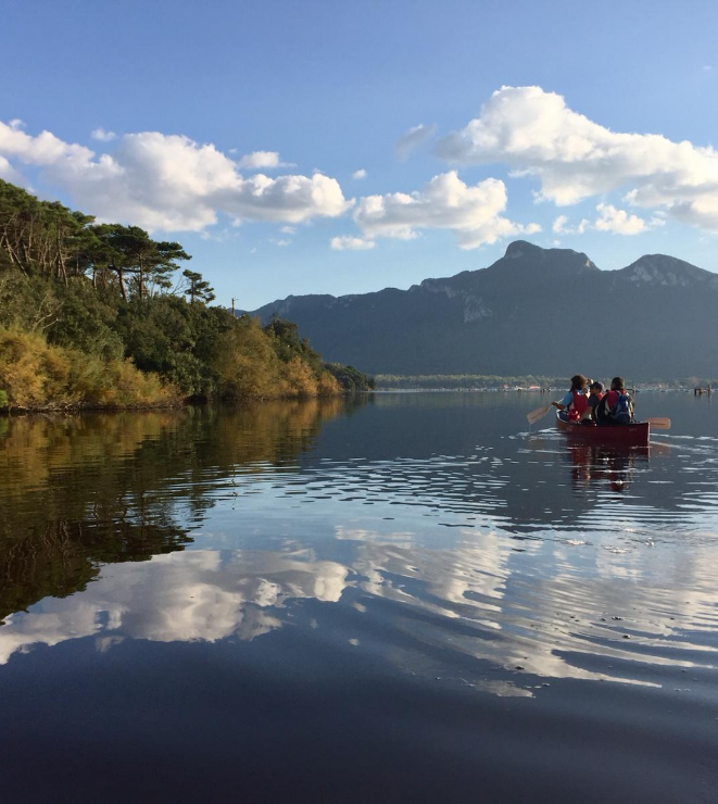 canoing surrounded by the hilly landscape with the sky reflected on the water
