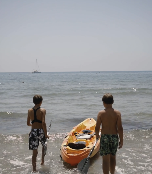 children entering the water with a canoe
