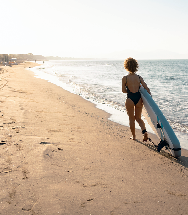 ragazza che porta tavola da sup sulla riva